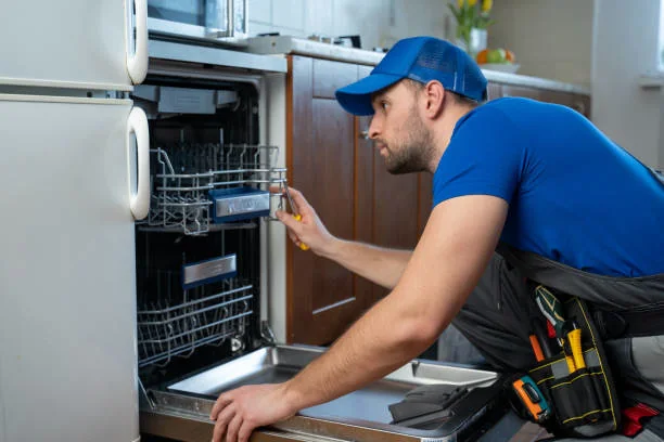 Appliance technician inspecting an open residential dishwasher