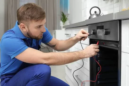 Technician testing electrical controls on a kitchen range